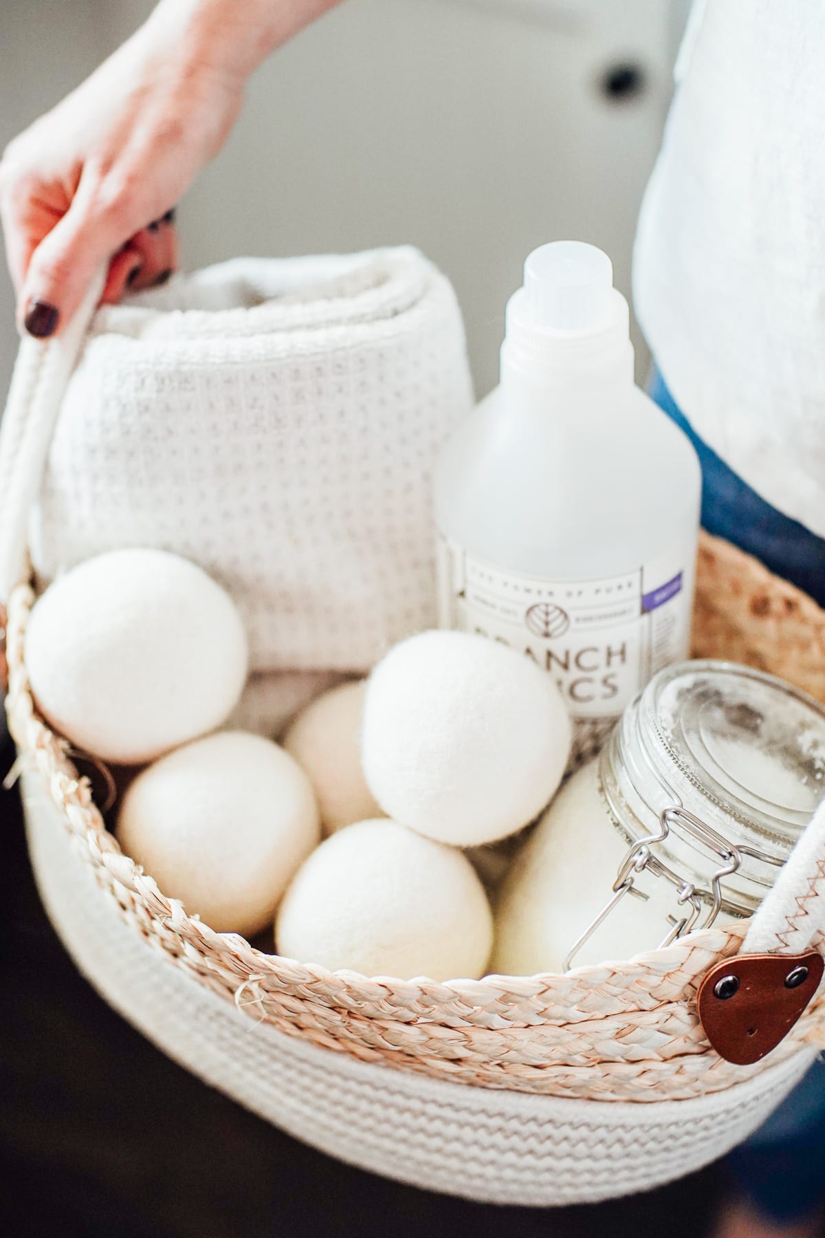 Laundry products (soap, softener, and wool dryer balls) in a laundry basket. 