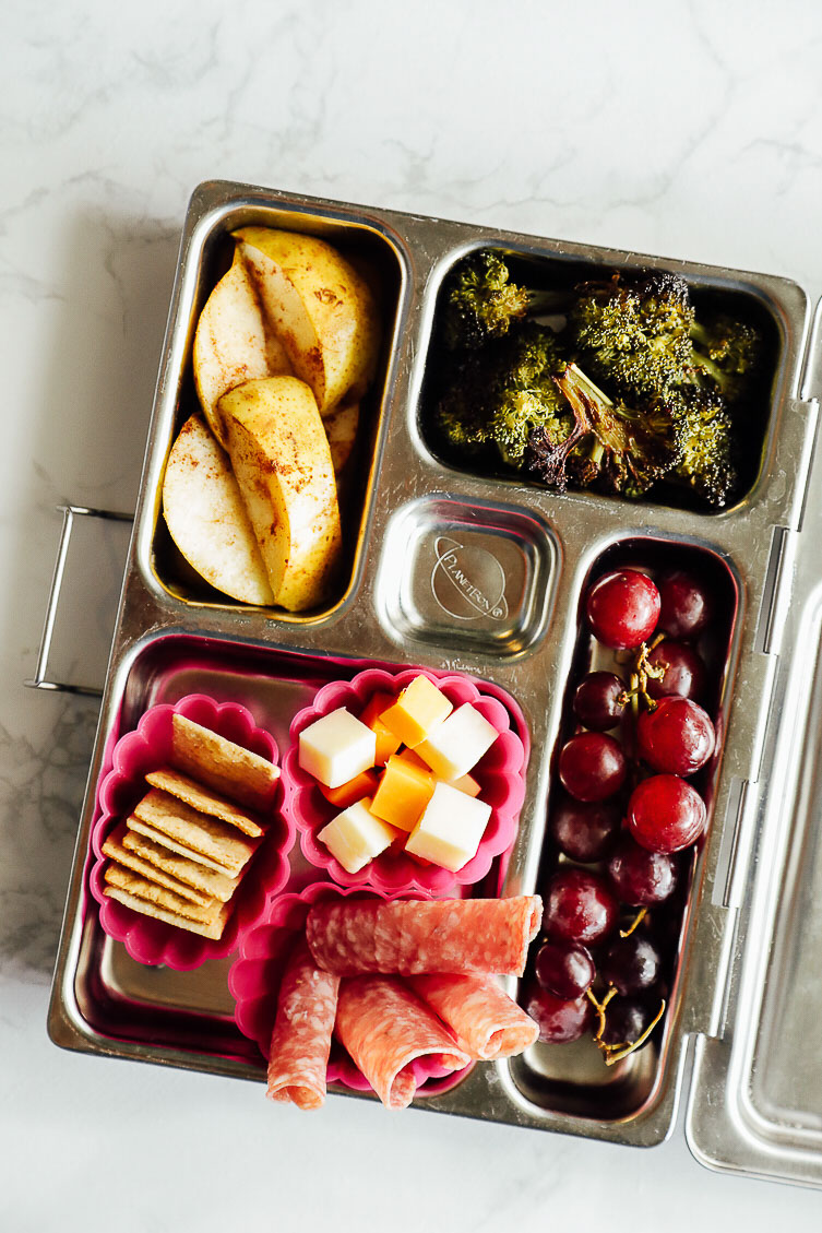 Homemade lunchable: crackers, cheese cubes, rolled up salami, grapes, pears, broccoli, crackers.