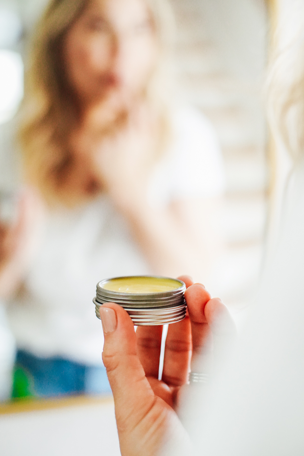 Shea butter lip balm in a tin, holding the tin in a hand. 