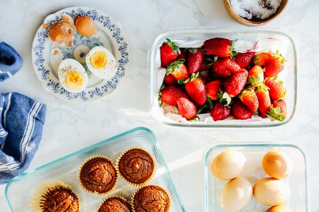 Easy breakfast items on a counter: hard-boiled eggs, strawberries, muffins.
