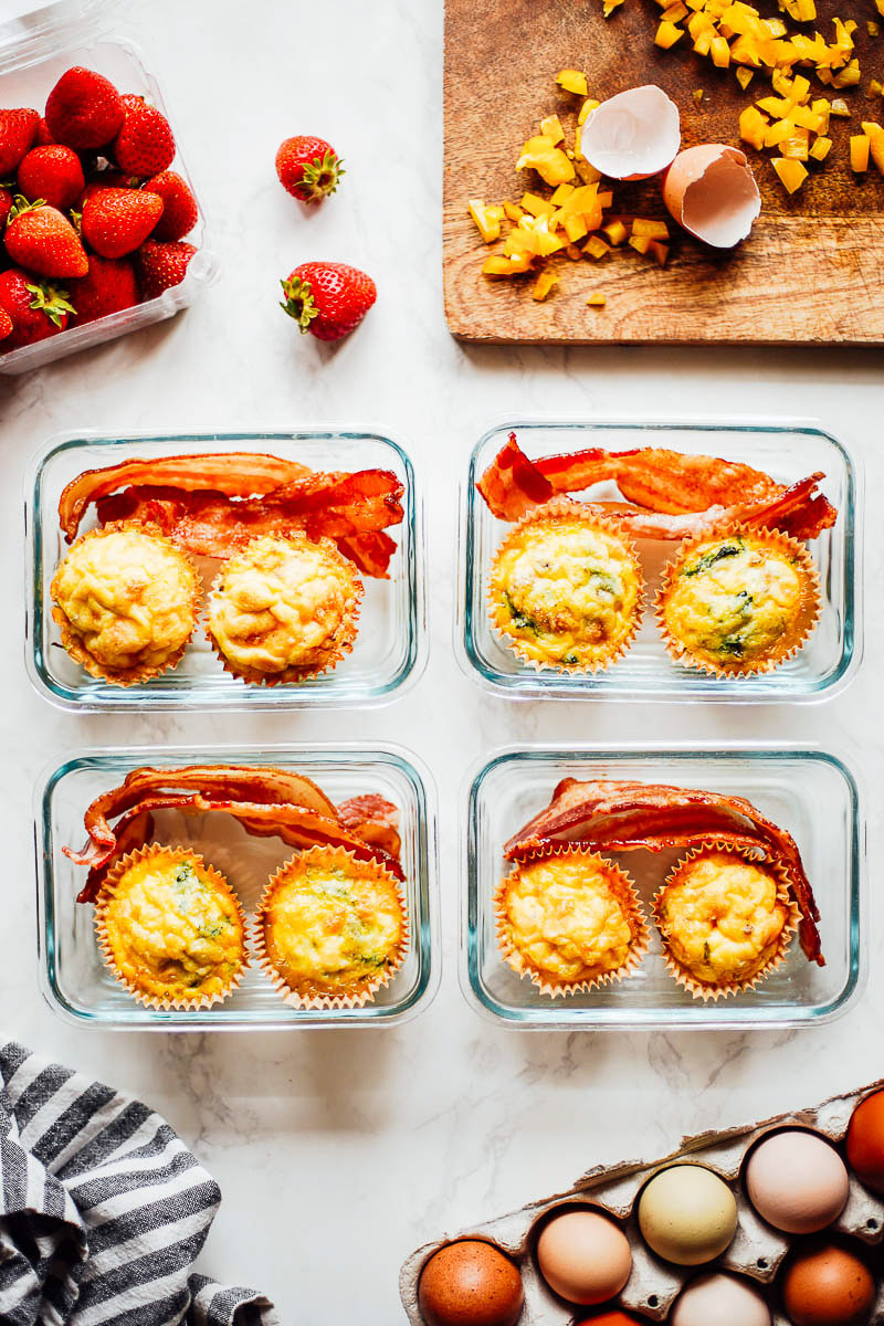 4 glass meal prep containers with egg cups inside and bacon.