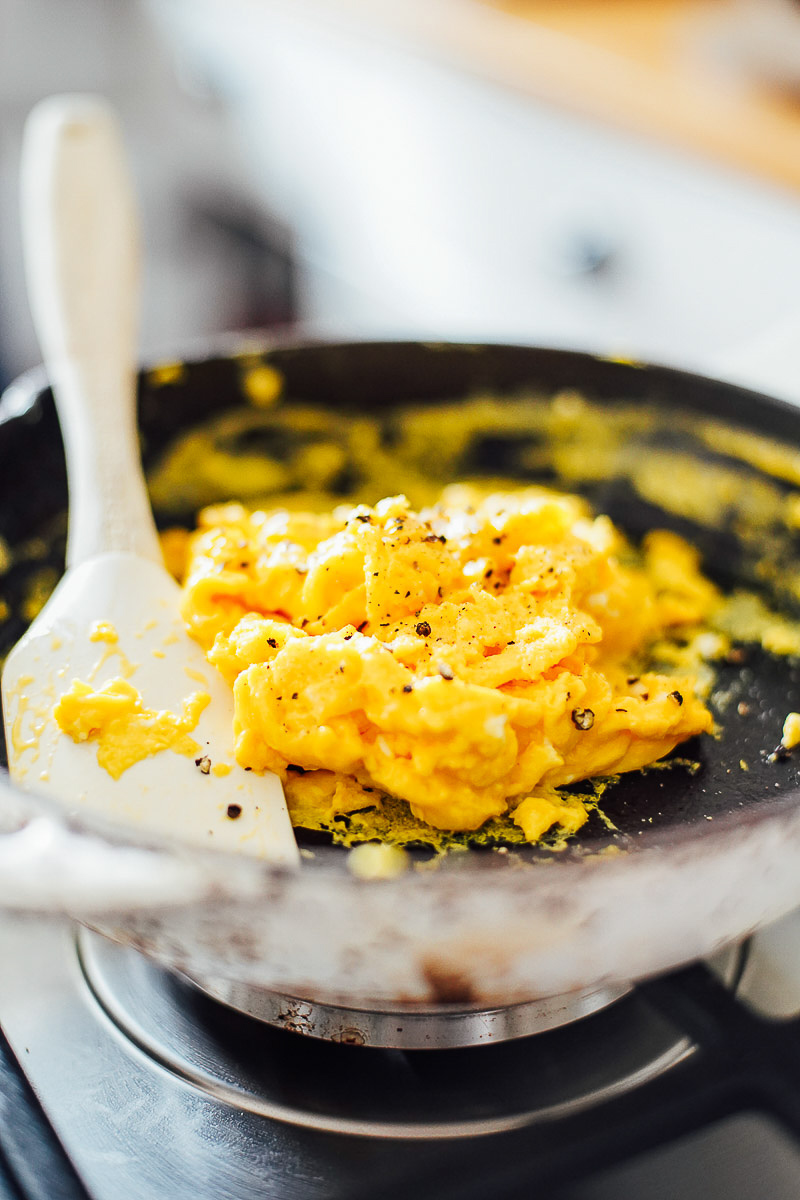 Scrambled eggs cooked in a cast iron skillet.