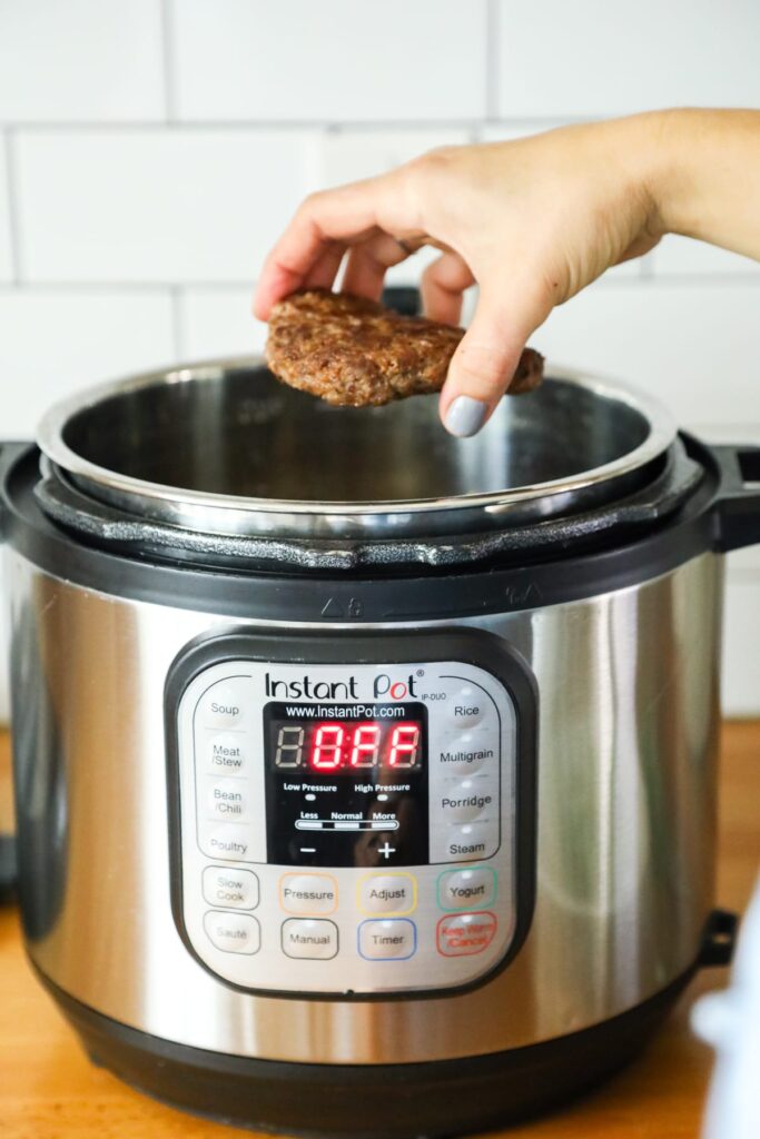Ground beef patties being pulled from the Instant Pot after browning. 