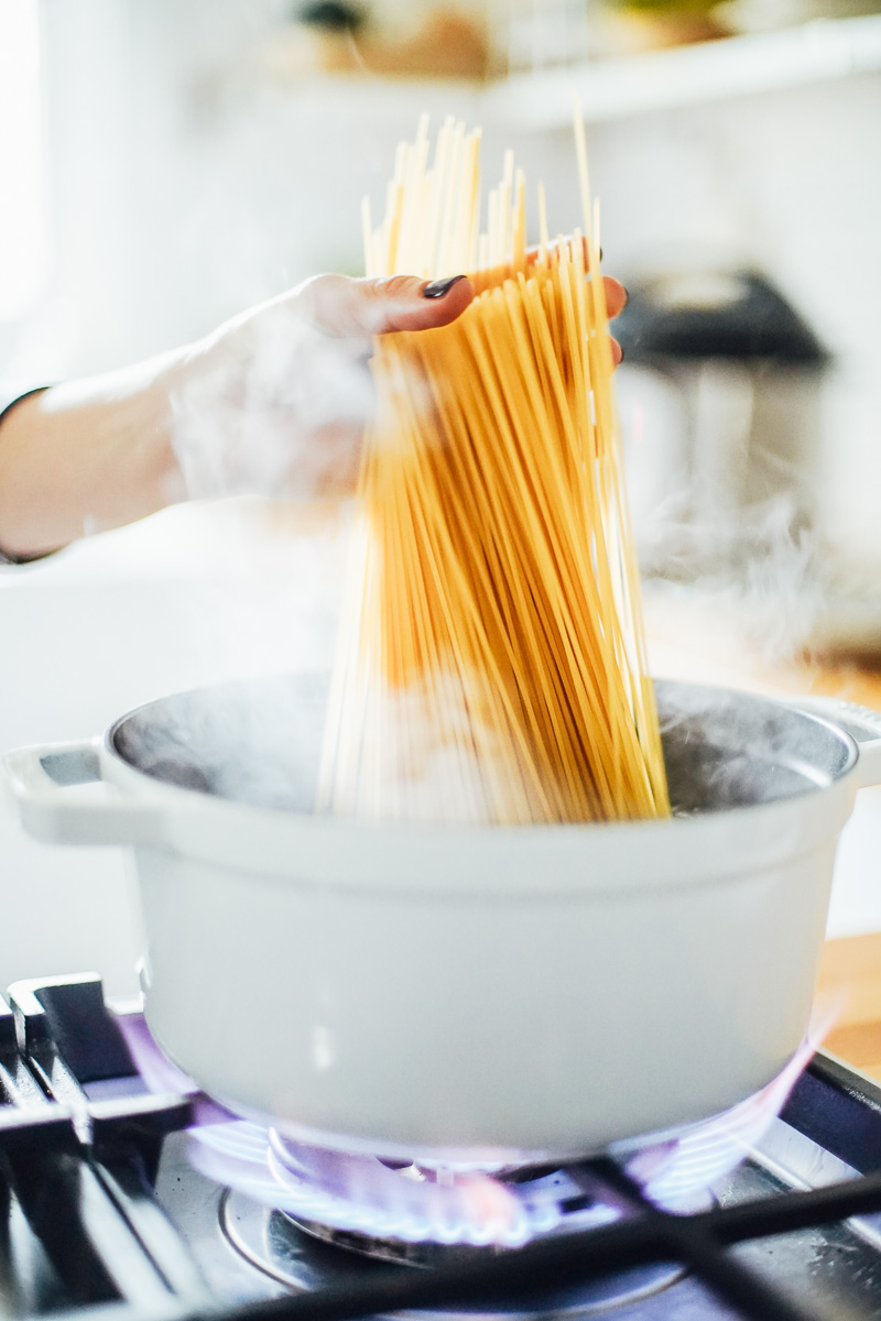 Adding pasta to hot water in a dutch oven.