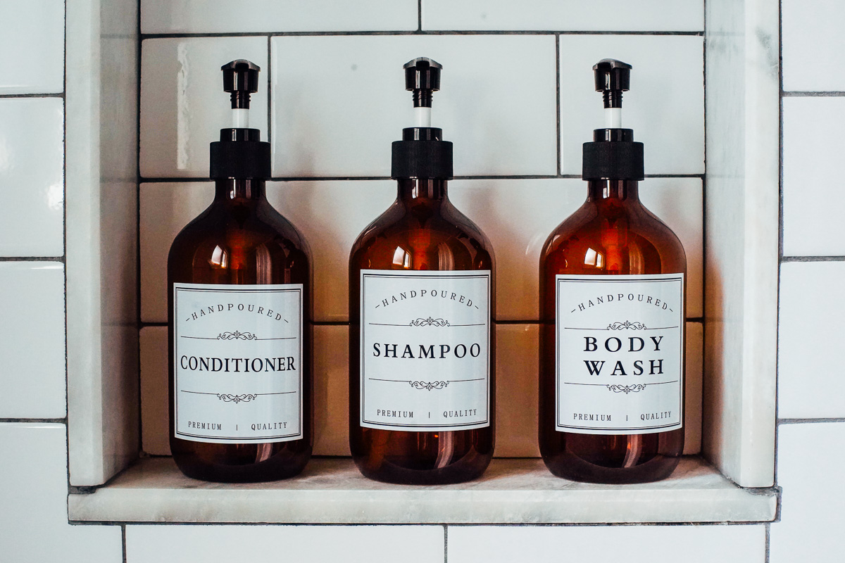 Shampoo, conditioner, and body wash in refillable amber bottles in the shower. 